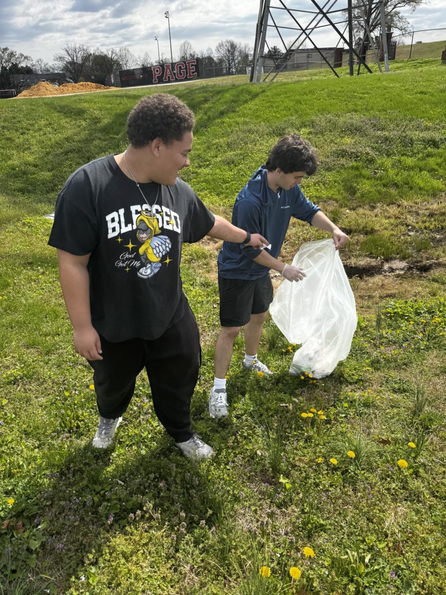 Jameson Stout points to trash for Aiden Scroggins to put in the bag.